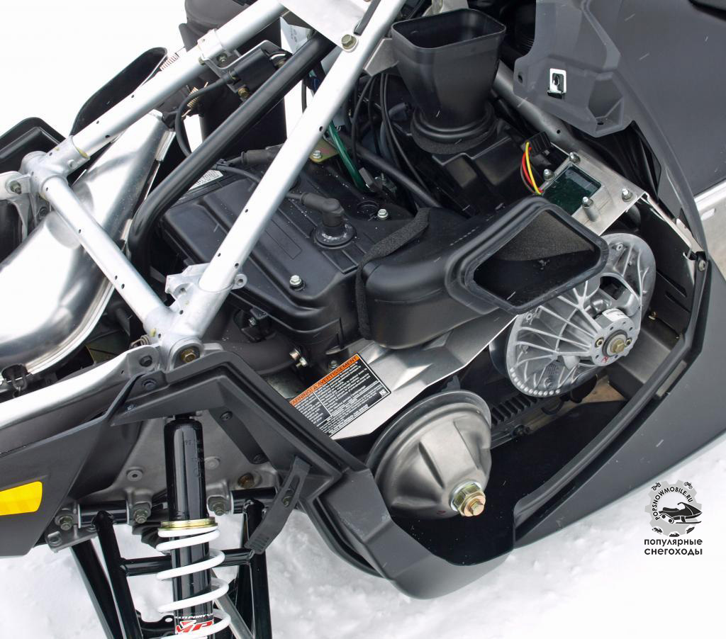 Использование 550-кубового двигателя с воздушным охлаждением потребовало множество воздуховодов и переход на сцепление от CVTech. Обратите внимание на треугольную конструкцию над двигателем, придающую снегоходу устойчивости и жёсткости.